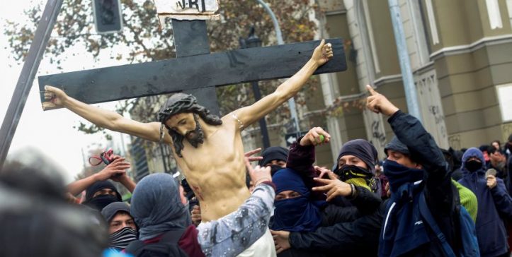 Masked demonstrators carry a cross with Jesus Christ, taken from inside a church during a protest against government education reforms in Santiago, Chile June 9, 2016. REUTERS/Pablo Sanhueza FOR EDITORIAL USE ONLY. NO RESALES. NO ARCHIVE.